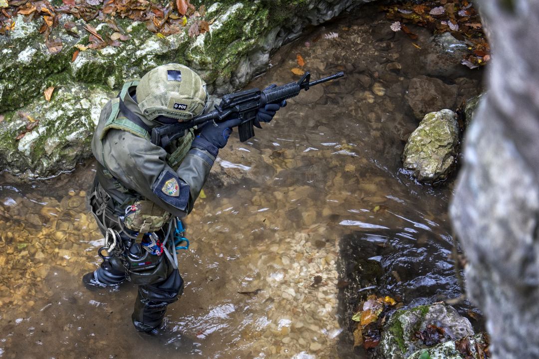 Operators in drysuits moving through a stream